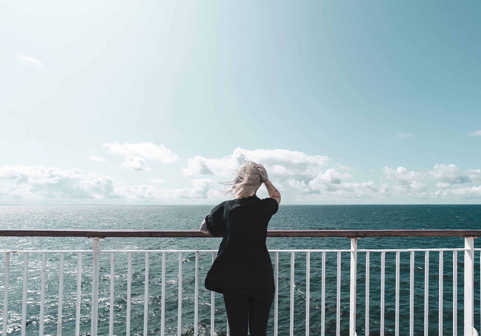 Woman on the ferry deck's railing with wind in her hair
