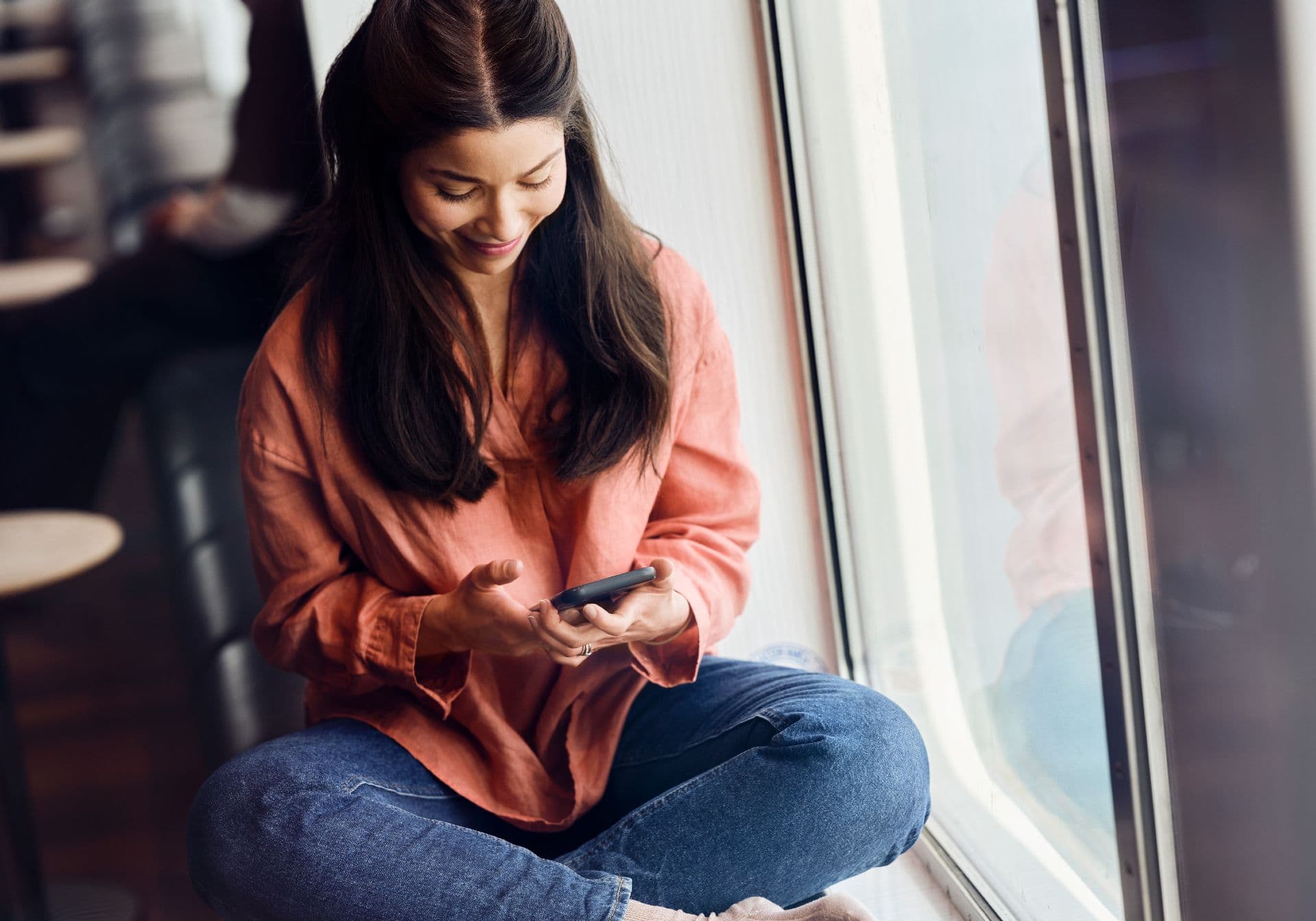 Woman sitting in window in the ferry using her phone