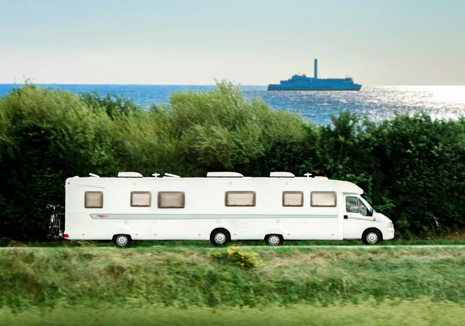 Autocamper kører langst kysten hvor man kan se Scandlines færge ude på havet